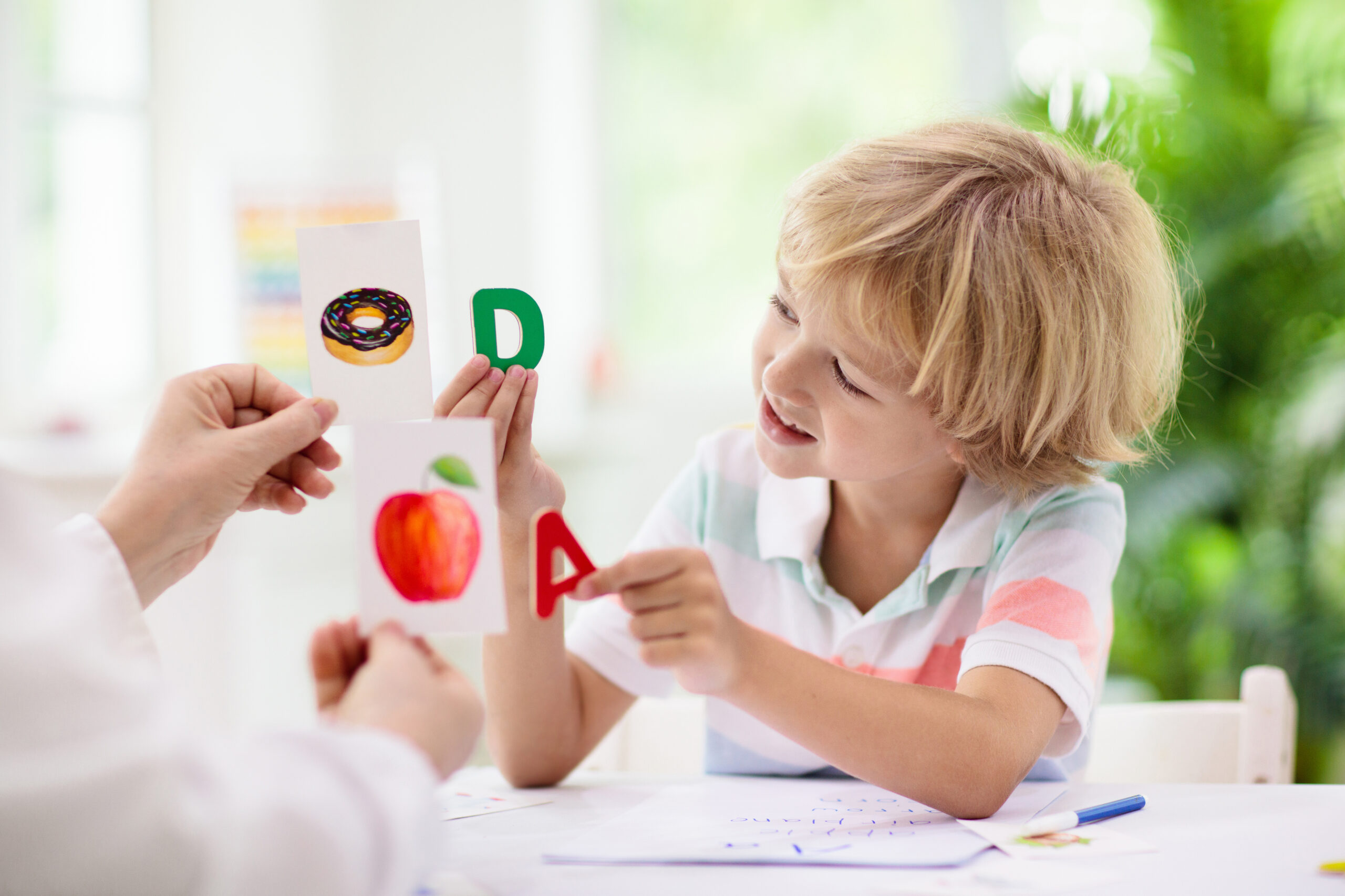 Young child learning phonics with letter cards, practicing reading and letter recognition in a playful, interactive educational setting.
