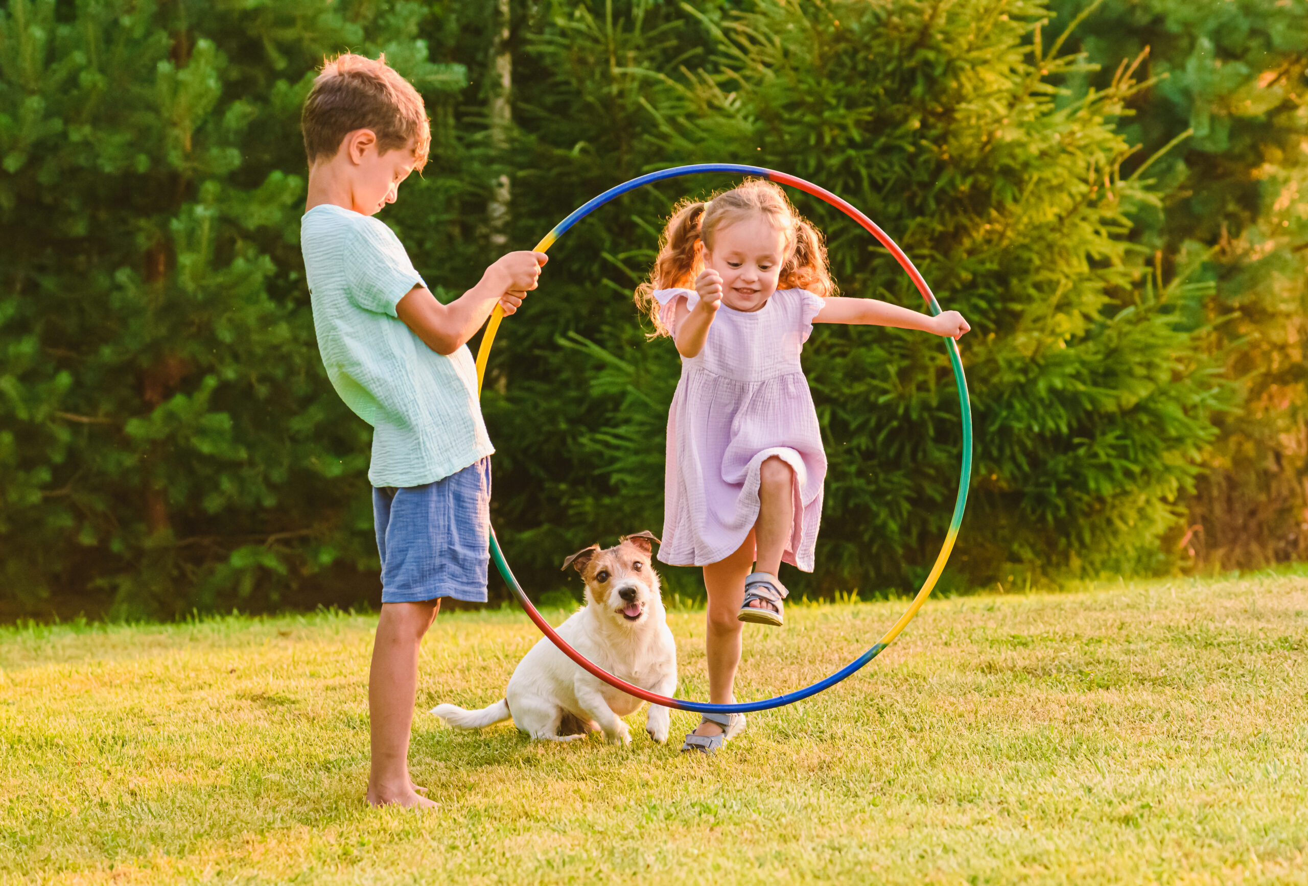 Outdoor play supporting gross motor skills development as children run, jump, and practice coordination with a hula hoop