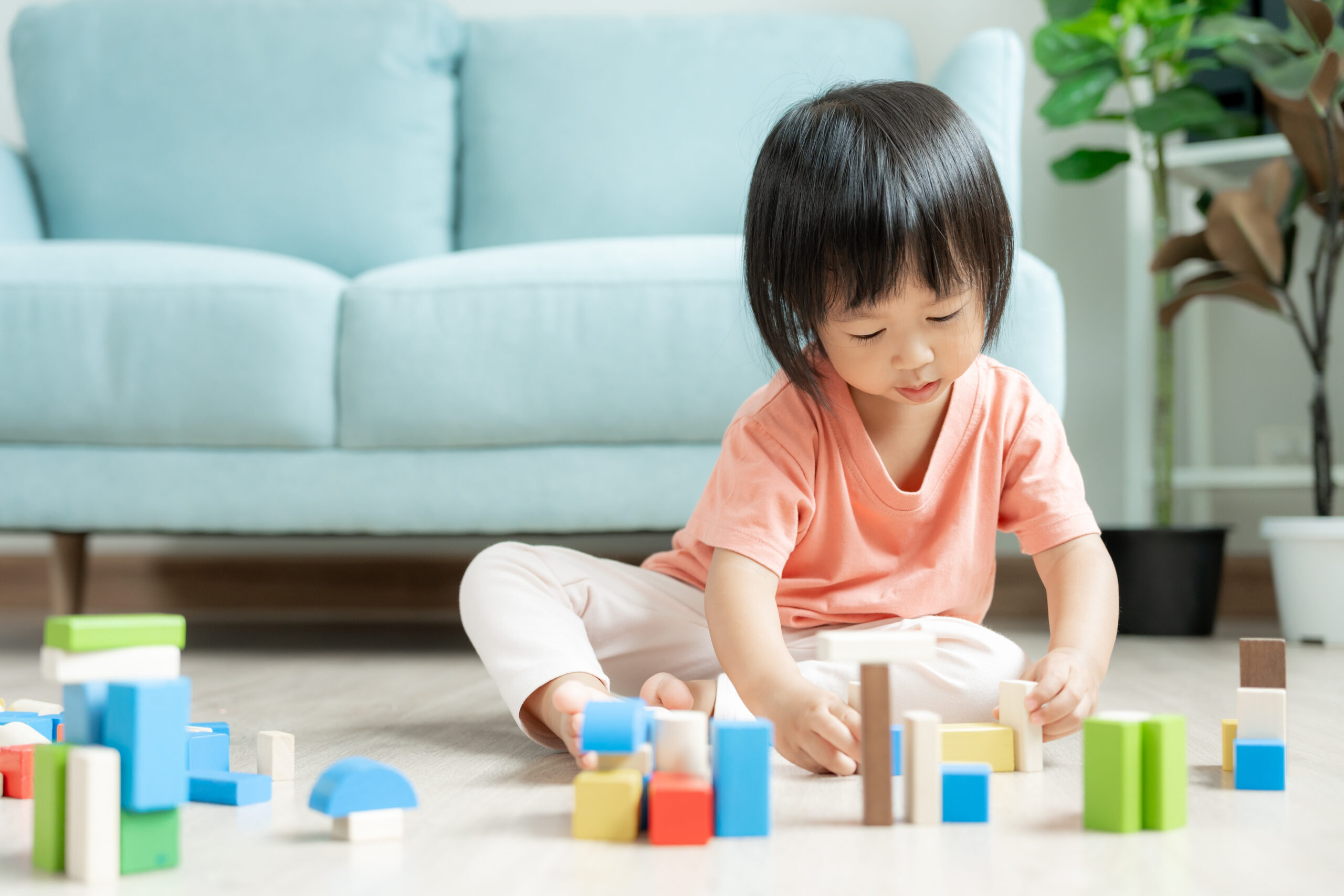 Toddler stacking colorful wooden blocks at home, practicing 2-year-old developmental milestones