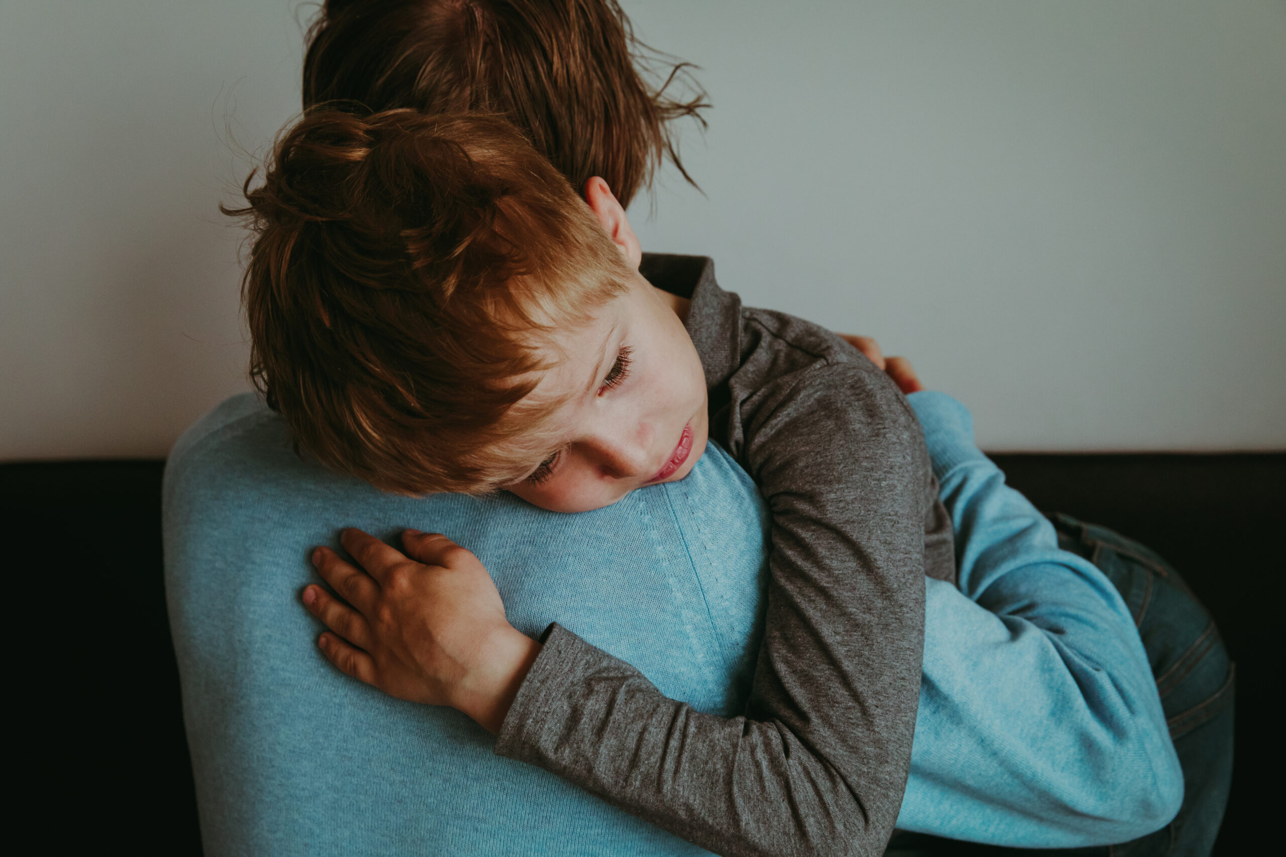Parent hugging a sad young child, offering comfort and emotional support.