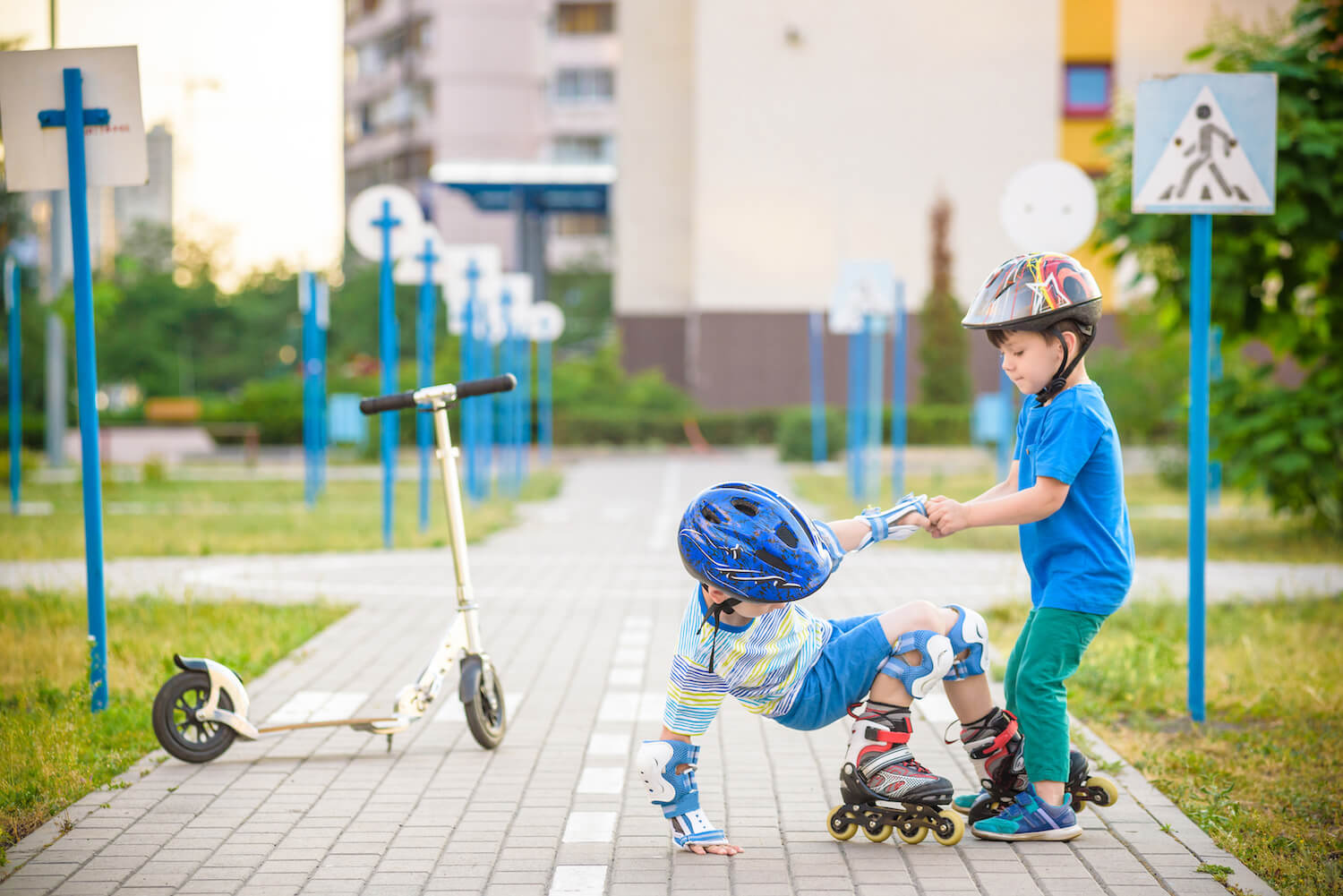 Child helping friend stand up after fall, demonstrating kindness, empathy, and friendship outdoors.