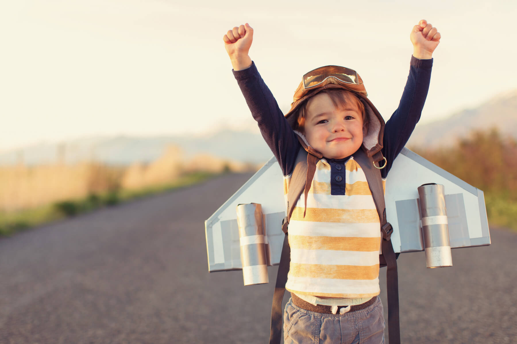Young child with homemade jetpack raising arms in triumph, symbolizing confidence and growth in executive function skills.