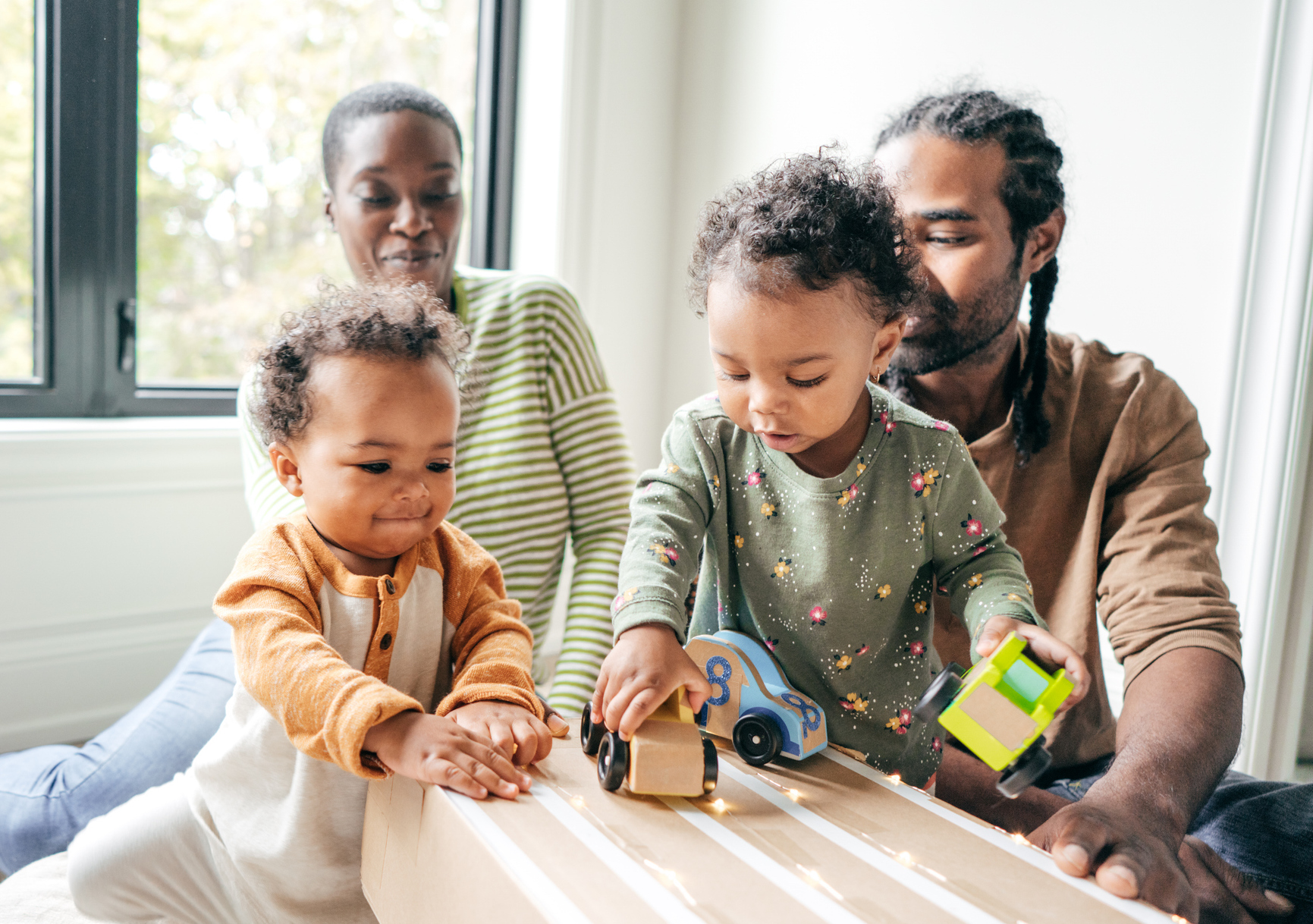 Learning activity with toddlers and parents exploring toys together to build motor skills, creativity, and early language.