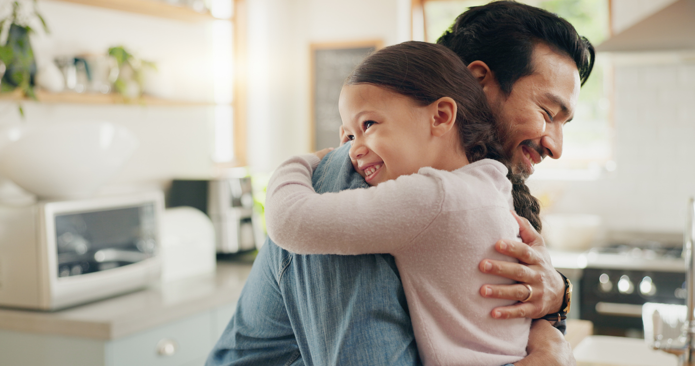 Father and daughter hug in the kitchen for love, trust or bonding together in their home illustrating a feel of gratitude.