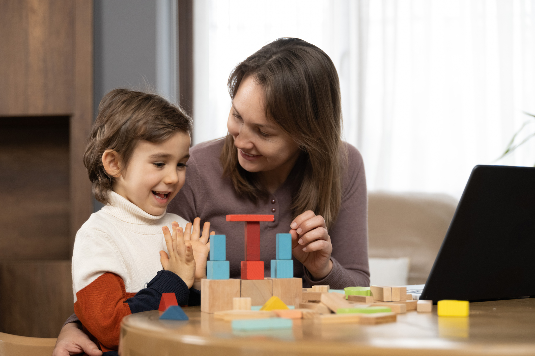 Mother and young child building colorful wooden blocks together at home to support problem-solving and cognitive flexibility.