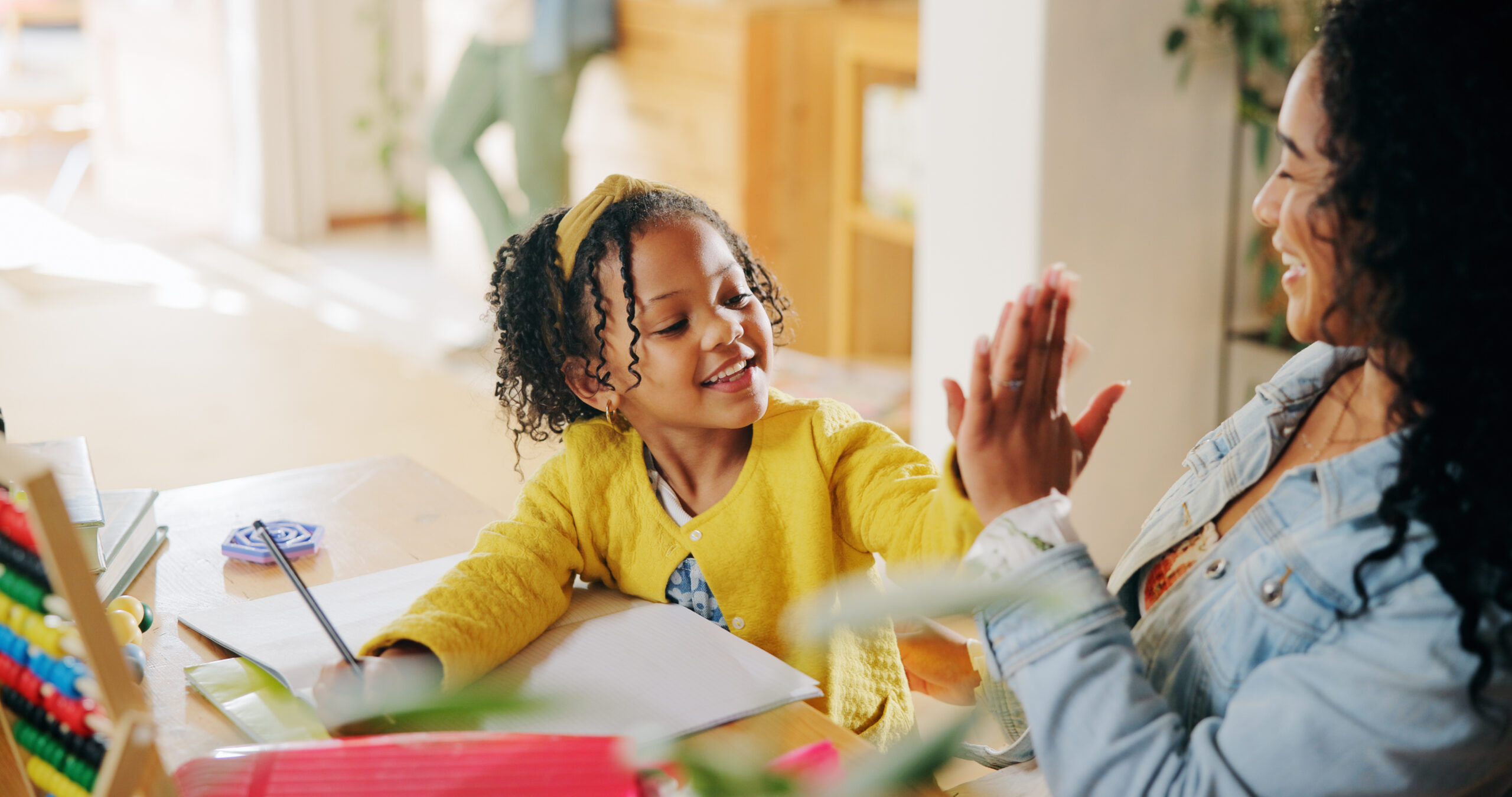 Parent and young child sharing a high five during a learning activity at home