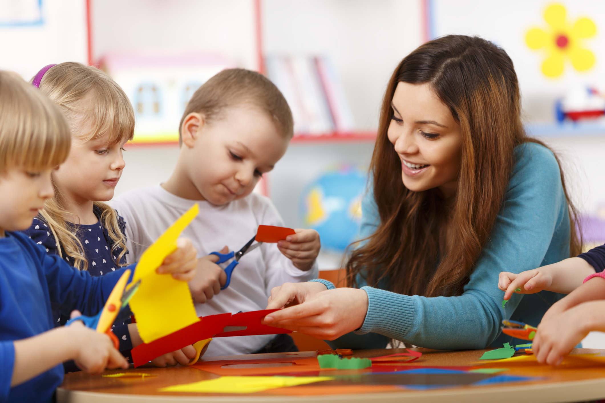 Teacher guiding preschool children in a hands-on classroom activity with paper crafts