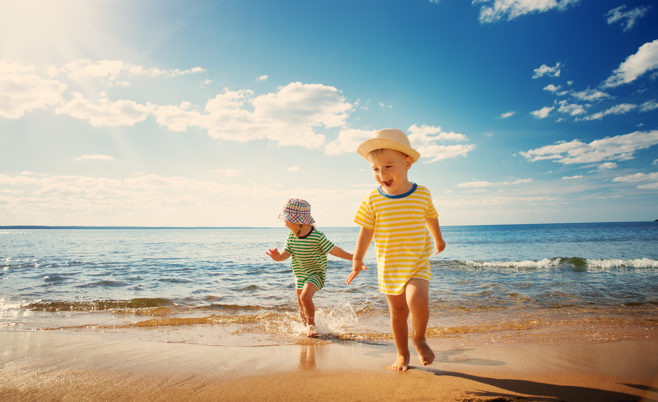 Two young children playing by the ocean and exploring the beach on a sunny day