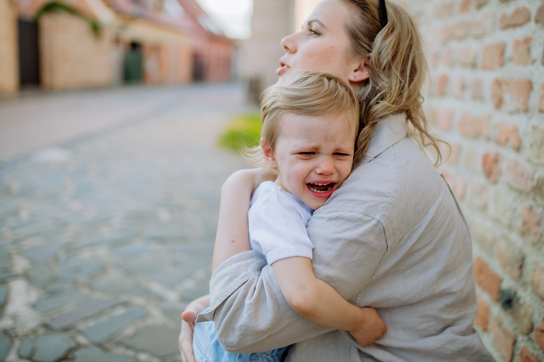 Crying young child hugging their mother for comfort during an emotional meltdown.